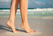 summer vacation and pedicure concept - closeup of woman legs walking on exotic beach sand