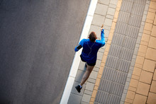 Top View Of Man Running On The Street. On Arm Smart Phone. Healthy Lifestyle Concept.
