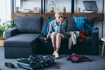 depressed woman sitting with glass of red wine and crying while packing in living room after breaking up with boyfriend