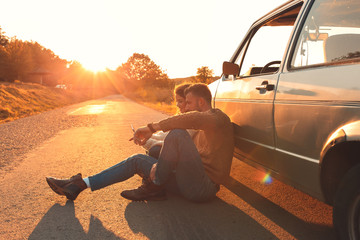 Wall Mural - Beautiful couple on road trip, they are taking a break from driving and looking for direction on tablet.