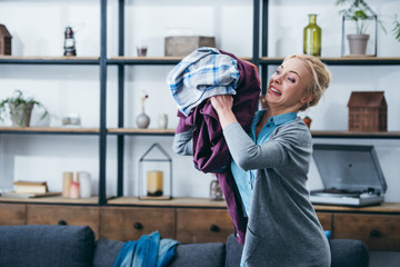 Wall Mural - angry woman throwing clothes in living room after breaking up with boyfriend