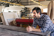 © mavoimages - Craftsman leaning on a workshop bench deep in thought