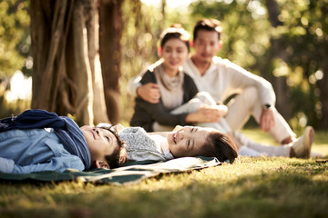 asian family with two children relaxing in park