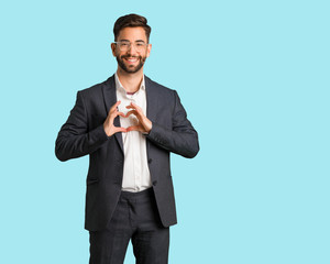 Young handsome business man doing a heart shape with hands