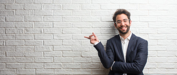 Young friendly business man pointing to the side, smiling surprised presenting something, natural and casual