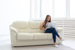 © satura_ - Freelance and people concept - Young woman sitting on a sofa and working at laptop