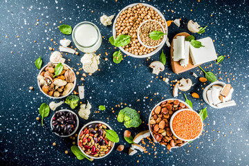 Wall Mural - Healthy plant vegan food, veggie protein sources: Tofu, vegan milk, beans, lentils, nuts, soy milk, spinach and seeds. Dark blue concrete background copy space