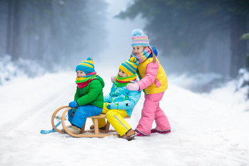 Wall Mural - Kids play in snow. Winter sleigh ride for children