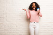 Young black woman screaming happy, surprised by an offer or a promotion, gaping, jumping and proud
