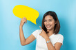 © suriya - Portrait of young girl holding a empty yellow speech bubble isolated on blue background