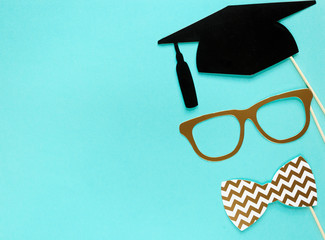 Creative background with photobooth props for graduation: hats, diploma, glasses, lips on bright blue paper background. Education, study concept. 