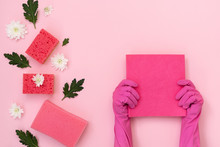 Woman In Pink Gloves Holding Pink Towel Against Background With Sponge And Flowers