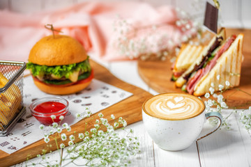 delicious lunch with cappuccino, sandwich, hamburger with french fries