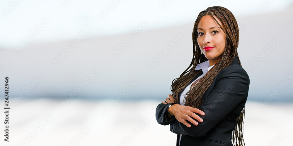 Portrait of a young black business woman crossing his arms, smiling and ...