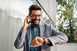 © phoenix021 - Handsome elegant businessman looking at wrist watch and talking on phone
