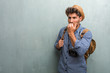 © Asier - Young handsome traveler man wearing a straw hat, a backpack and a photo camera biting nails, nervous and very anxious and scared for the future, feels panic and stress
