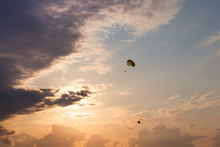 Dark Silhouettes Of Flying Parachutes On The Sunset Cloudy Night Sky