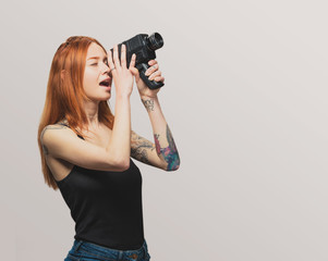 Wall Mural - portrait of a pretty redhead girl filming with a video camera