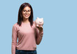 © Asier - Young pretty woman confident and cheerful, holding a piglet bank and being quiet because the money is saved, concept of saving, economy and prosperity