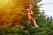 © Daniel CHETRONI - Happy kid with helmet and harness on zip line between trees