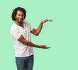 © Asier - Handsome african american holding something with hands, showing a product, smiling and cheerful, offering an imaginary object
