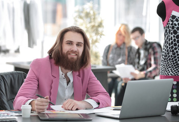 smiling fashion Designer at the table in a modern Studio