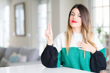 Young beautiful woman wearing winter sweater at home Swearing with hand on chest and fingers, making a loyalty promise oath