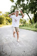 © Halfpoint - A small boy hopscotching on a road in park on a summer day.