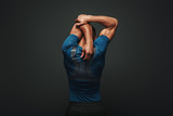 Even if you don't have time for a big workout, stretching in the morning and night really changes your body. Sportsman is stretching standing over dark background