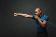 © Friends Stock - Full of energy. Sportsman working out with resistance band over dark background