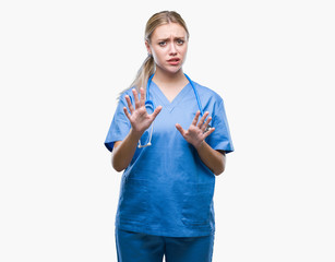 Wall Mural - Young blonde surgeon doctor woman over isolated background disgusted expression, displeased and fearful doing disgust face because aversion reaction. With hands raised. Annoying concept.