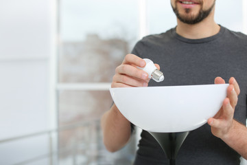 Man changing light bulb in lamp indoors, closeup with space for text