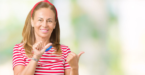 Sticker - Beautiful middle age woman wearing casual stripes t-shirt over isolated background Pointing to the back behind with hand and thumbs up, smiling confident