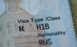 Fragment of H1B visa (for specialty workers) stamp in passport, blurred april calendar on background. H1B visa program deadline concept. Close up view.