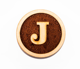 Wall Mural - J, wooden alphabet letter - Ground organic coffee. Top view