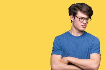 Young handsome man wearing glasses over isolated background skeptic and nervous, disapproving expression on face with crossed arms. Negative person.