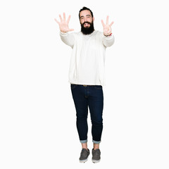 Wall Mural - Young man with long hair and beard wearing sporty sweatshirt showing and pointing up with fingers number eight while smiling confident and happy.