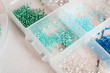 © lesyakih - colored beads in transparent plastic boxes on a wooden table