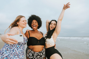 Wall Mural - Beautiful curvy women taking a selfie at the beach