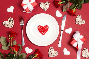 Wall Mural - Festive table setting with cutlery, rose flowers and gift boxes on red table. Flat lay, top down composition.