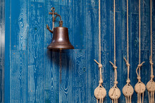 Copper Old Vintage Bell, Doorbell, Rope On A Wooden Blue Aged Wall. Concept Decor Element In Interior Of Deck, Cabin Of Ship, Restaurant, Room, House Decorated On Marine Theme