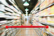 © Kwangmoozaa - Empty shopping cart with abstract blur supermarket discount store aisle and product shelves interior defocused background