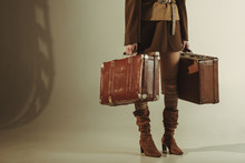 Partial View Of Fashionable Woman Holding Vintage Suitcases On Beige