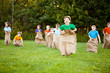 © IdeaBug, Inc. - Happy Kids Having Potato Sack Race Outside