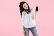 © LIGHTFIELD STUDIOS - surprised brunette girl showing smartphone with blank screen, isolated on pink