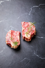 Wall Mural - Raw Fresh Marbled Meat Beef Steak with rosemary on a black background.Top View Copy space for Text