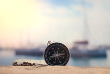 Time To Travel. An Idea For Tourism With A Compass In The Sand With Corals In The Background Of The Sea And A Parking For Yachts.