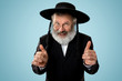 Portrait of old senior orthodox Hasdim Jewish man with wooden Grager Ratchet at Jewish festival of Purim at studio. The purim, jewish, festival, holiday, celebration, judaism, pastry, tradition