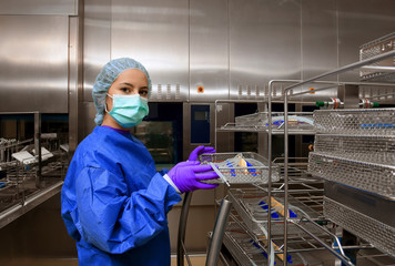 Wall Mural - A young woman works in a hospital as a  medical hygiene technician. She is dressed  in special medical hygiene clothing and  carries out hygiene disinfecting and logistic tasks.