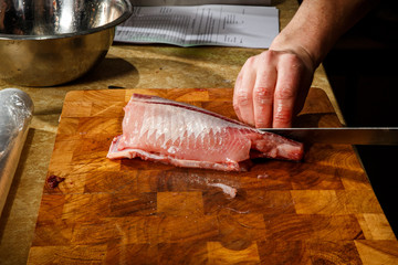 closeup chef hands cut fish fillet by knife